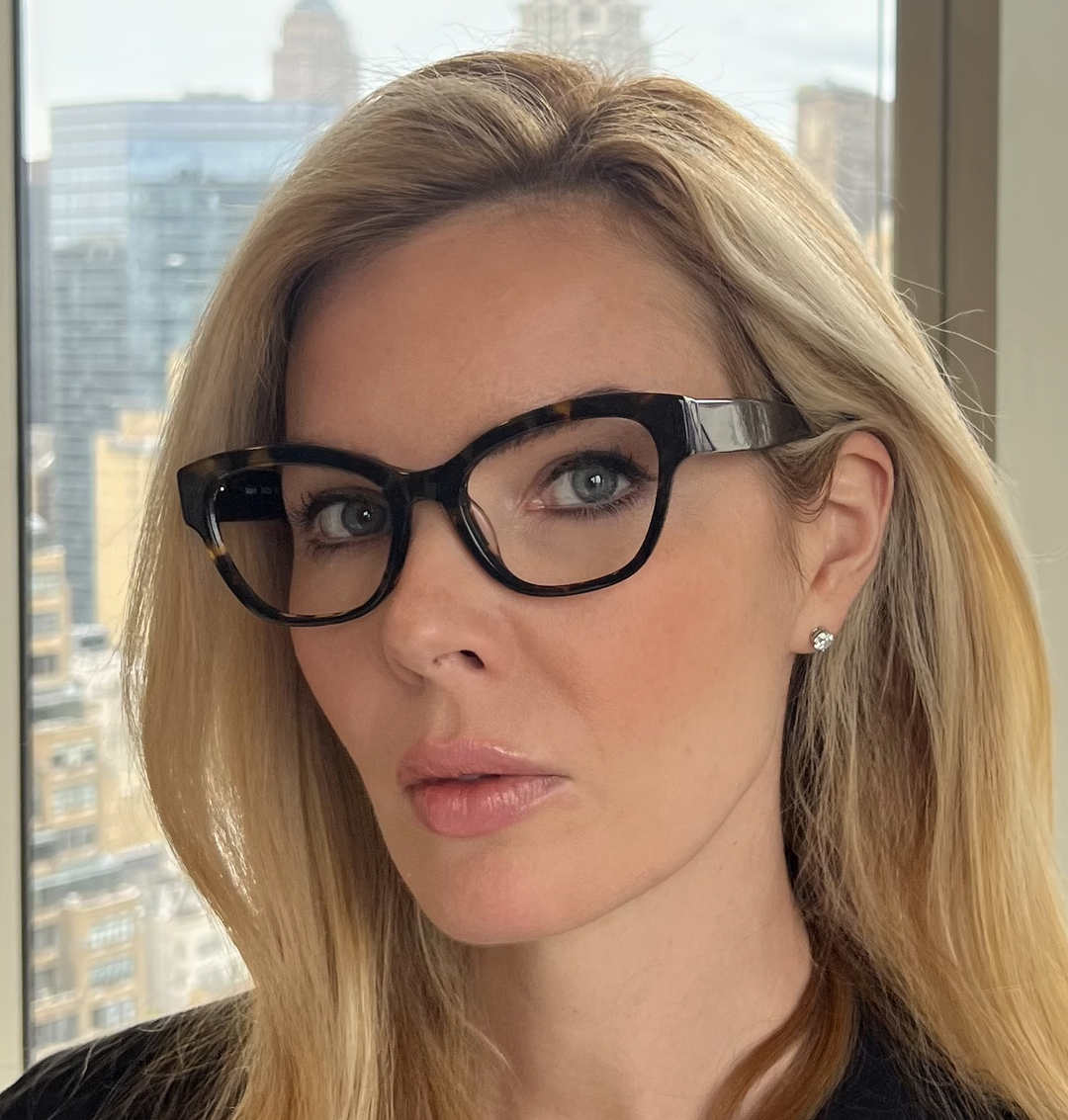 Woman wearing glasses with a cityscape  Renee's Readers