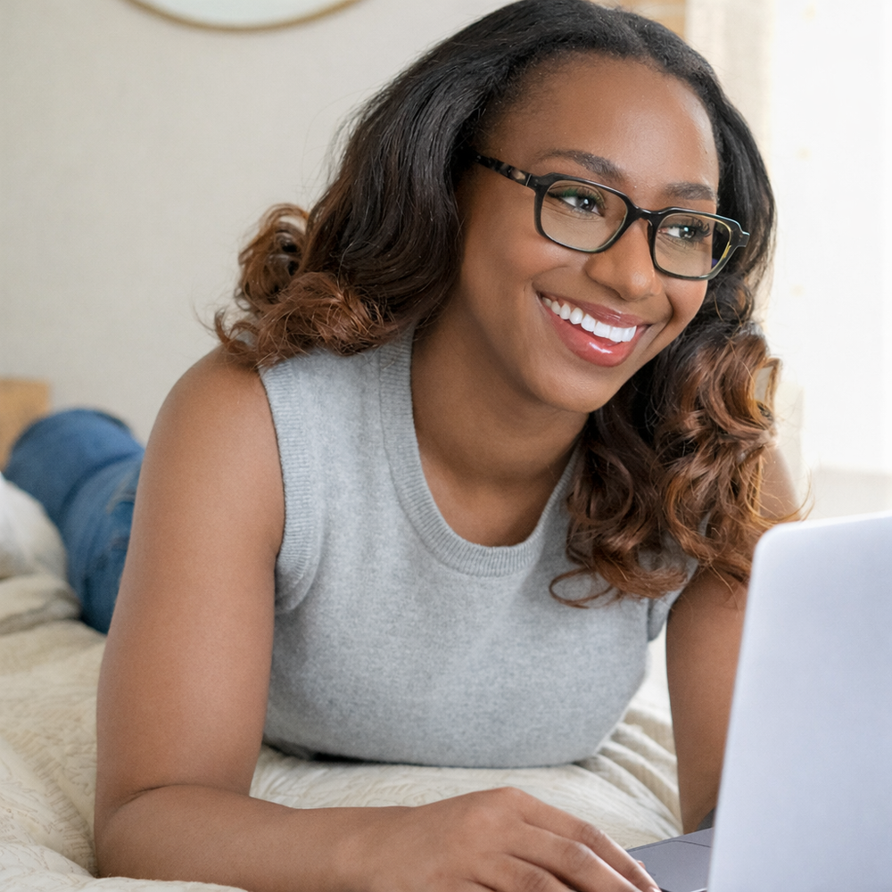 wearing reading glasses l on a bed using a laptop | RENEE'S READERS