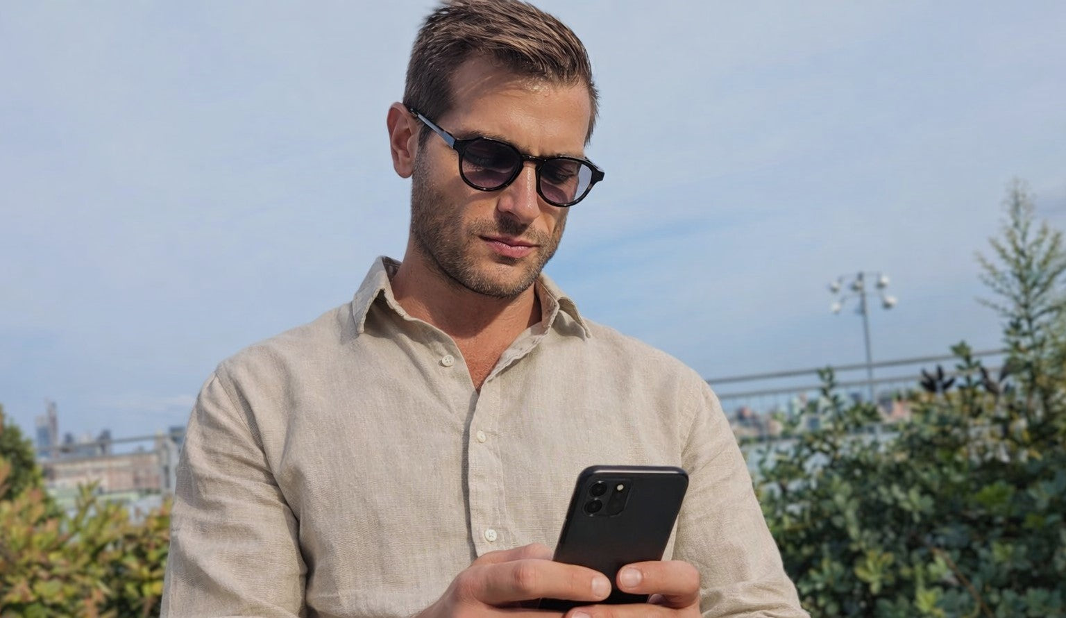 Man wearing reading sunglasses looking at his phone 
